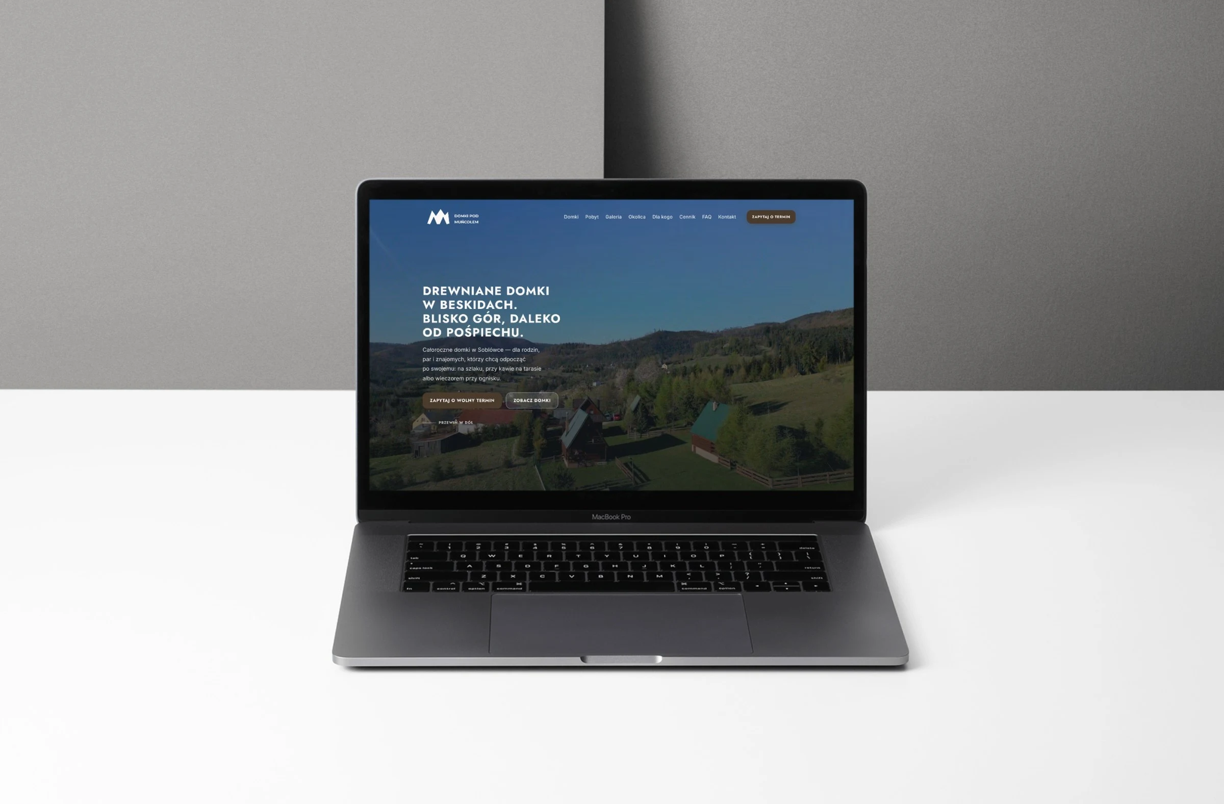 domkipodmuncolem.pl — projekt strony internetowej, mockup macbook scena biurko
