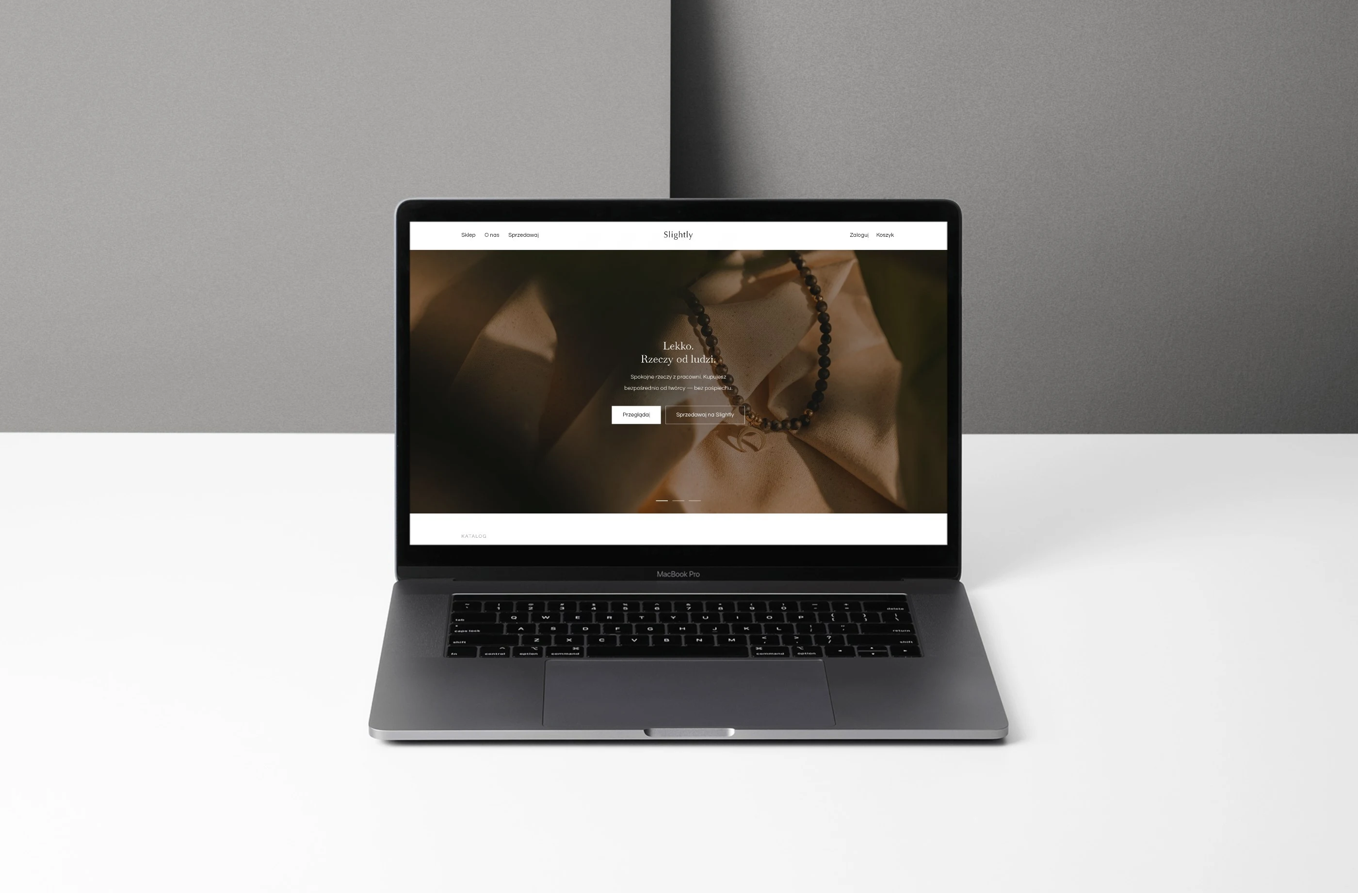 Slightly na MacBooku: strona główna marketplace rękodzieła z naszyjnikiem z kamieni i przyciskiem „Przeglądaj”